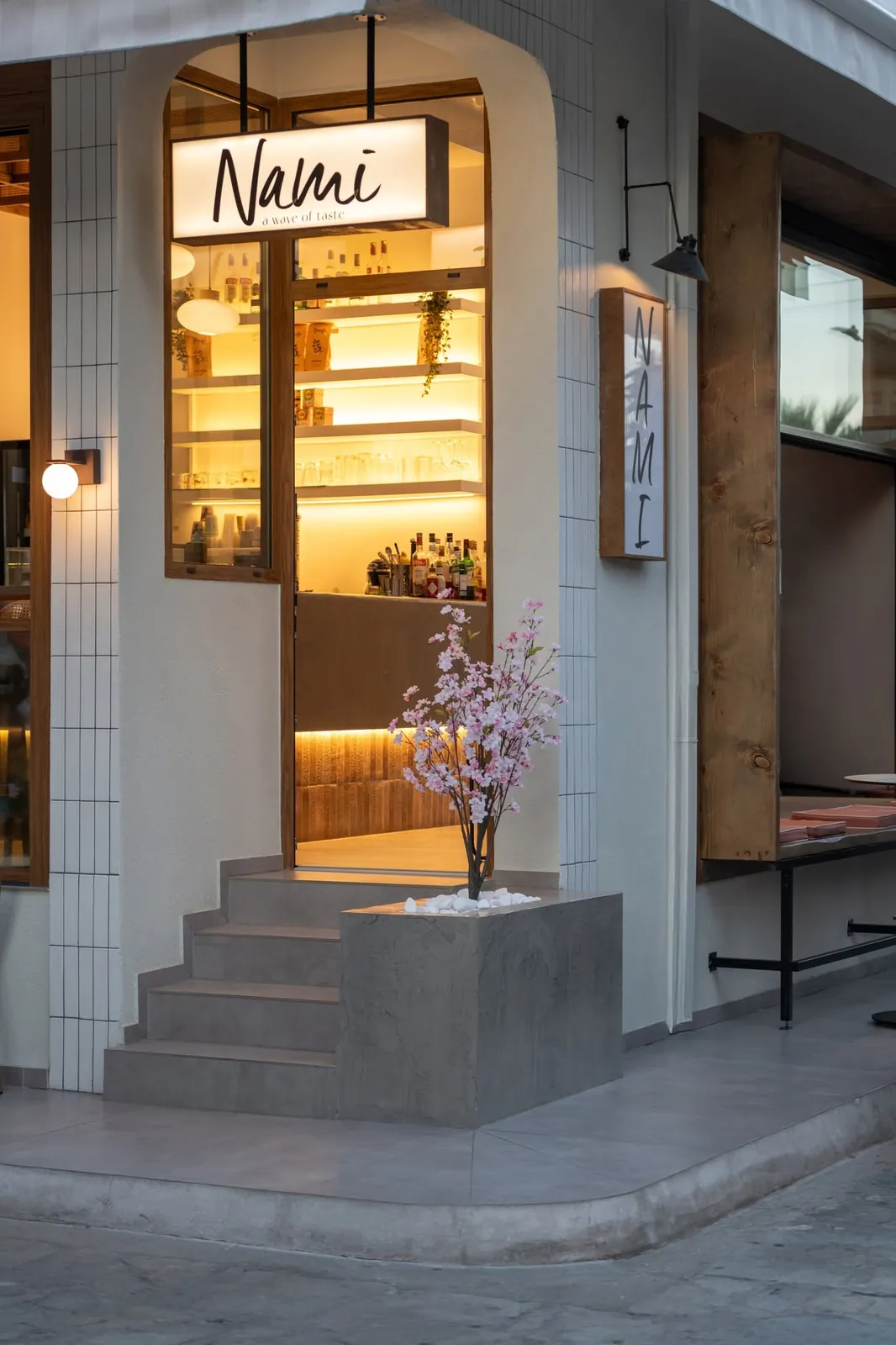 The lit entrance of Nami in the evening with the a wave of taste sign